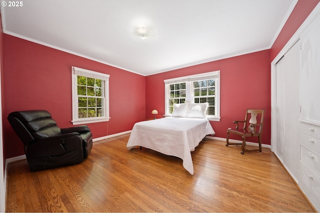 bedroom with ornamental molding, multiple windows, and light wood-style floors