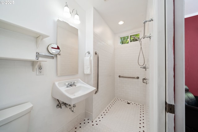 bathroom with a sink, toilet, recessed lighting, and a tile shower