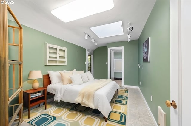 bedroom featuring rail lighting, a skylight, baseboards, and a walk in closet