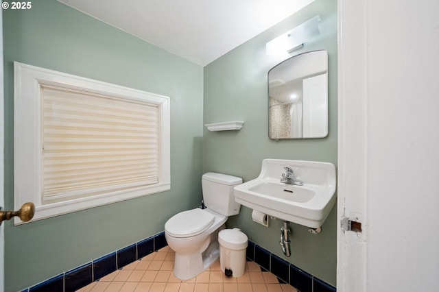 bathroom featuring toilet, baseboards, tile patterned flooring, and a sink