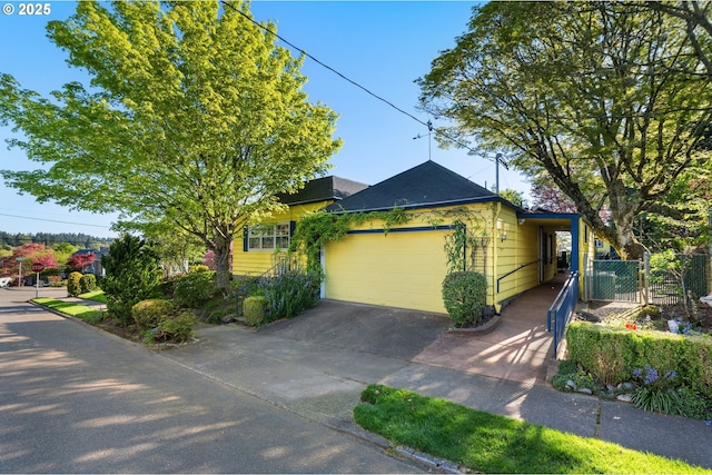 view of front of home featuring concrete driveway, roof with shingles, an attached garage, and fence