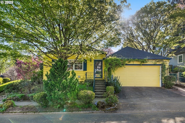 obstructed view of property featuring aphalt driveway, a garage, and fence