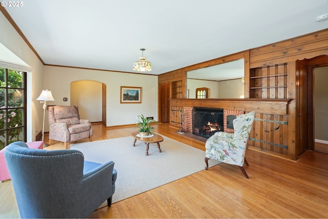 living room with ornamental molding, wood finished floors, arched walkways, and built in shelves
