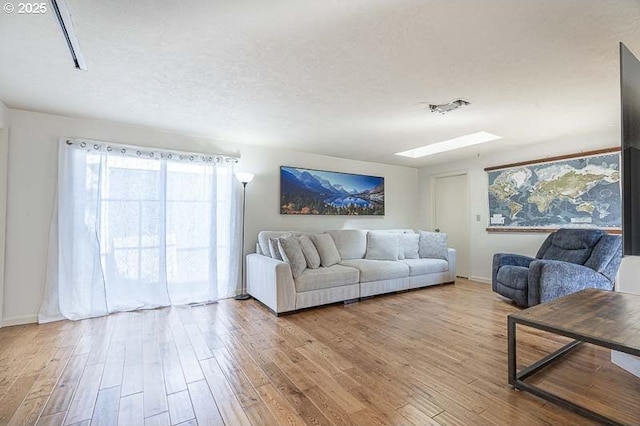 living area with baseboards, a textured ceiling, and wood finished floors