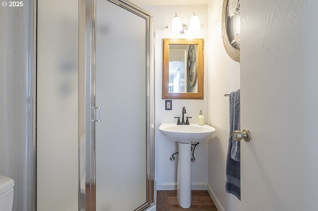 full bathroom with baseboards, a shower stall, toilet, and wood finished floors