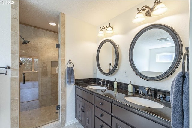 full bathroom with a sink, double vanity, a shower stall, and a textured ceiling
