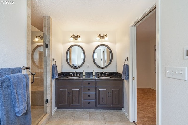 full bathroom featuring double vanity, a sink, baseboards, and a shower stall