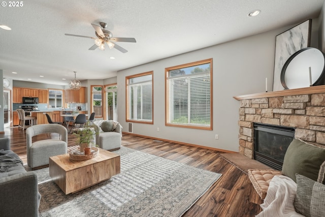 812 NW 13th Ave, Battle Ground, WA 98604 - living area with wood finished floors, a ceiling fan, a stone fireplace, a textured ceiling, and a chandelier