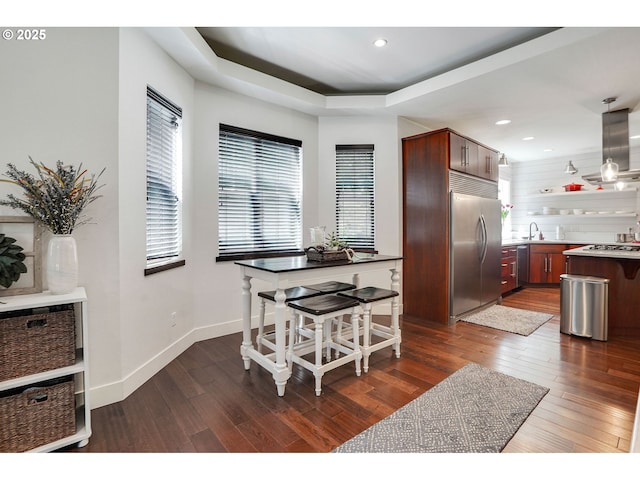 dining space with dark wood-type flooring, recessed lighting, a raised ceiling, and baseboards
