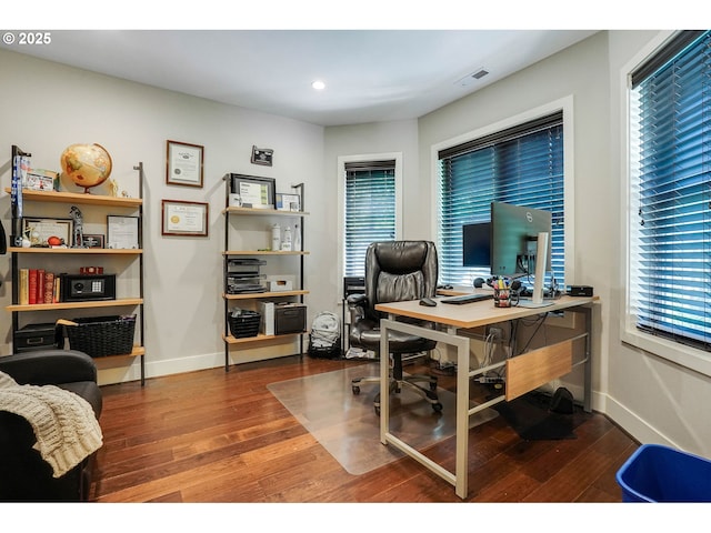 office space with a healthy amount of sunlight, baseboards, wood finished floors, and visible vents