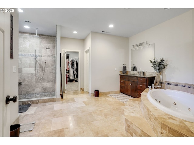bathroom featuring visible vents, vanity, a walk in closet, a whirlpool tub, and a stall shower