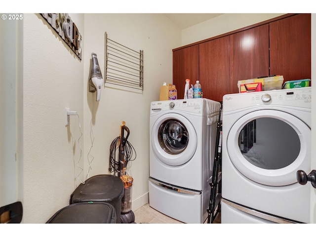 washroom featuring cabinet space, washer and clothes dryer, and light tile patterned floors
