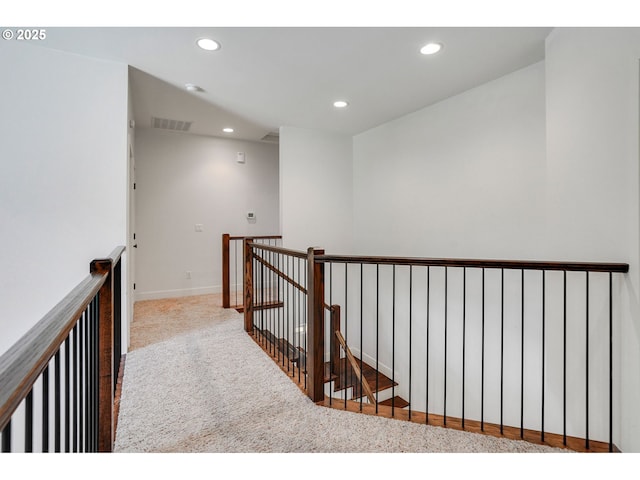 hall featuring carpet floors, visible vents, baseboards, recessed lighting, and an upstairs landing