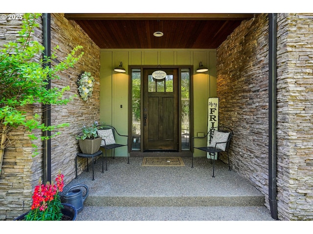view of exterior entry featuring a porch and stone siding