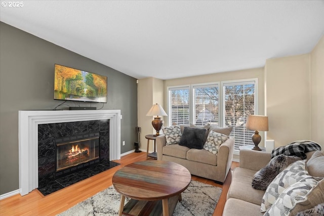 living room with hardwood / wood-style flooring, a premium fireplace, and vaulted ceiling