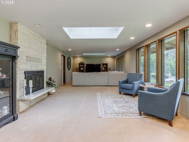 carpeted living area with recessed lighting, a skylight, and a stone fireplace