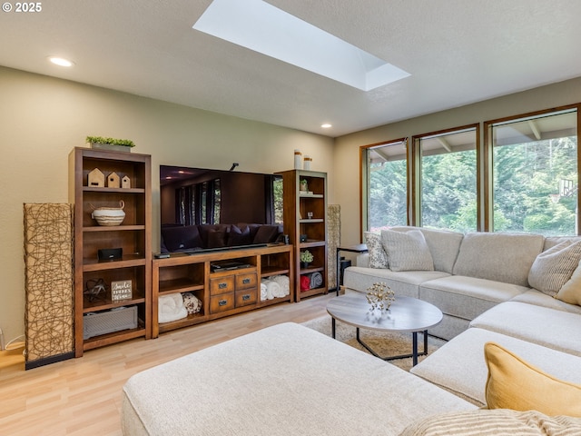 living area featuring a skylight, recessed lighting, and light wood finished floors