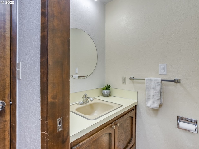 bathroom with a textured wall and vanity