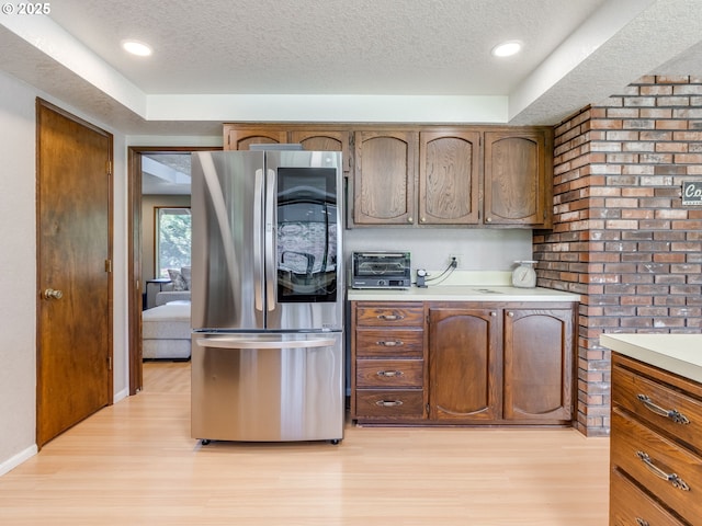kitchen featuring a textured ceiling, smart refrigerator, light countertops, a toaster, and light wood-style flooring