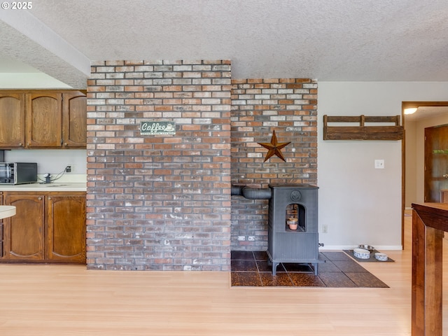 living area featuring baseboards, a wood stove, a textured ceiling, and wood finished floors