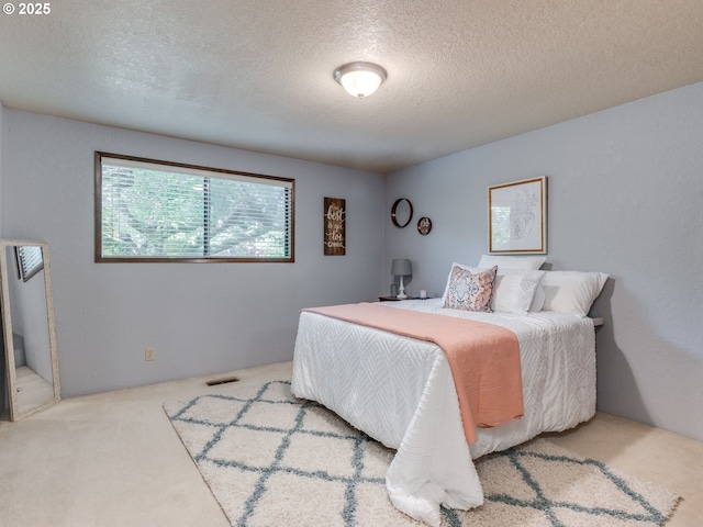 bedroom with visible vents, a textured ceiling, and carpet