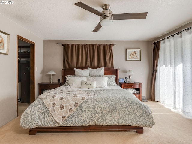 bedroom with a textured ceiling, ceiling fan, and light carpet