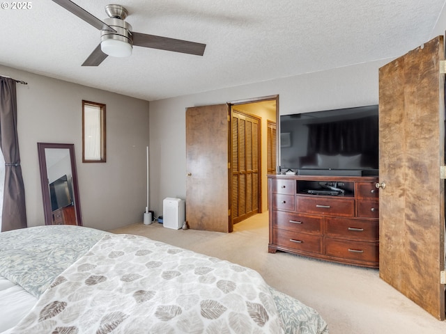 bedroom with light colored carpet, a ceiling fan, a textured ceiling, and a closet