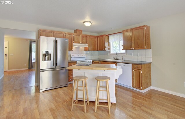 10808 NE 92nd Cir, Vancouver, WA 98662 - kitchen featuring white appliances, under cabinet range hood, light wood-type flooring, and decorative backsplash