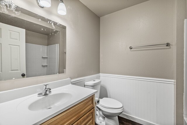 bathroom featuring vanity, wood-type flooring, a shower, and toilet