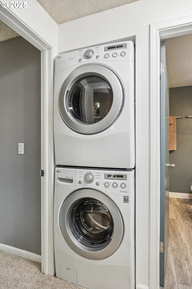 5160 SW 180th Ave Unit 17, Beaverton, OR 97078 - laundry room with stacked washer / drying machine, a textured ceiling, and baseboards