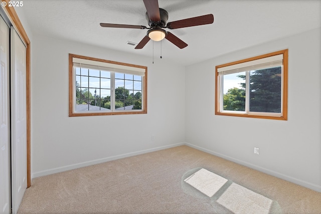 921 SE 168th Ave, Portland, OR 97233 - unfurnished bedroom featuring multiple windows, carpet flooring, a closet, and a ceiling fan