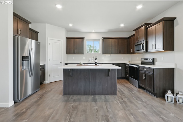 4236 E Willakenzie St, Newberg, OR 97132 - kitchen featuring stainless steel appliances, dark brown cabinetry, a center island, wood finished floors, and light countertops
