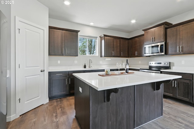 4236 E Willakenzie St, Newberg, OR 97132 - kitchen featuring stainless steel appliances, a breakfast bar area, dark brown cabinets, a kitchen island with sink, and light countertops