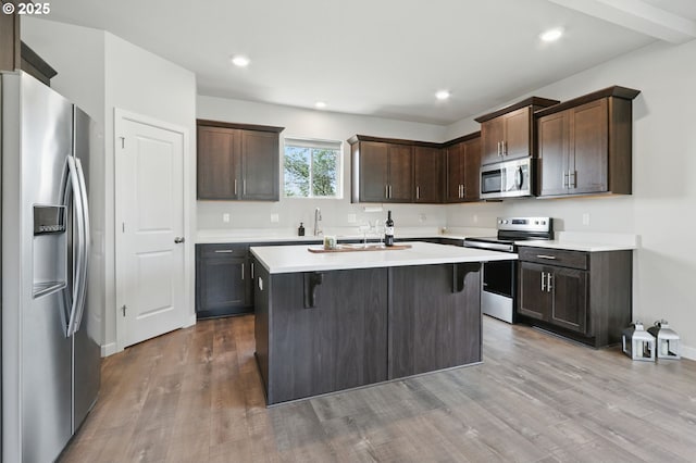 4236 E Willakenzie St, Newberg, OR 97132 - kitchen featuring stainless steel appliances, dark brown cabinetry, a center island, light countertops, and wood finished floors