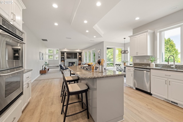 10695 SW Meier Dr, Tualatin, OR 97062 - kitchen with appliances with stainless steel finishes, open floor plan, a center island, a breakfast bar area, and a fireplace