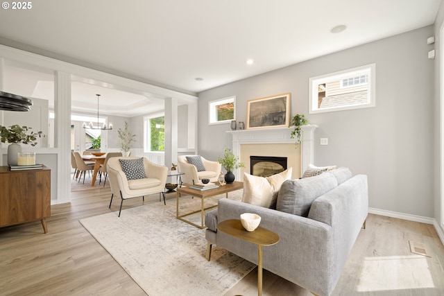 10695 SW Meier Dr, Tualatin, OR 97062 - living room featuring a fireplace, light wood-type flooring, a chandelier, a raised ceiling, and recessed lighting