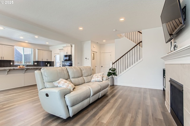 1319 S 29th Blvd, Cornelius, OR 97113 - living area featuring light wood-type flooring, stairway, a tiled fireplace, recessed lighting, and baseboards