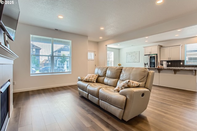 1319 S 29th Blvd, Cornelius, OR 97113 - living room featuring a fireplace, wood finished floors, recessed lighting, baseboards, and a textured ceiling