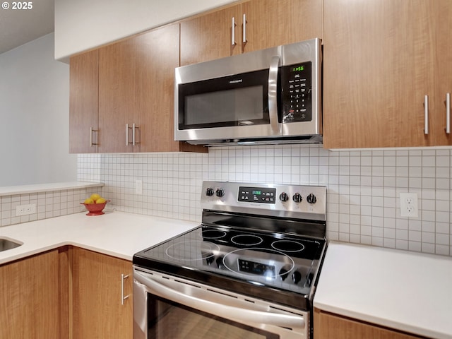 kitchen featuring stainless steel appliances, backsplash, light countertops, and brown cabinets