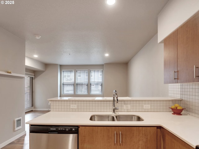 kitchen with light countertops, a sink, backsplash, and stainless steel dishwasher