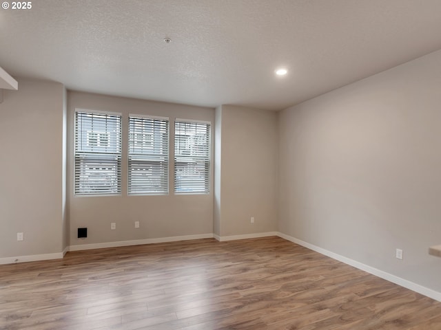 unfurnished room featuring light wood-style flooring, baseboards, and a textured ceiling