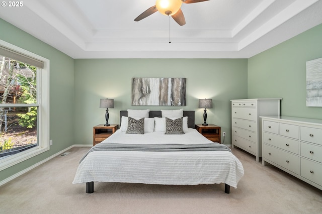 bedroom featuring a tray ceiling, a ceiling fan, baseboards, and light carpet