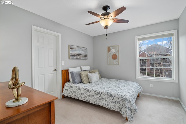 bedroom featuring light colored carpet, a ceiling fan, and baseboards