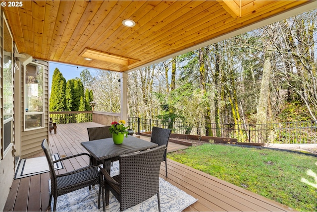 wooden terrace featuring outdoor dining area, a yard, and fence