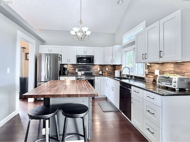 2942 NW Watkins Ct, Camas, WA 98607 - kitchen with appliances with stainless steel finishes, a chandelier, a kitchen breakfast bar, white cabinetry, and high vaulted ceiling