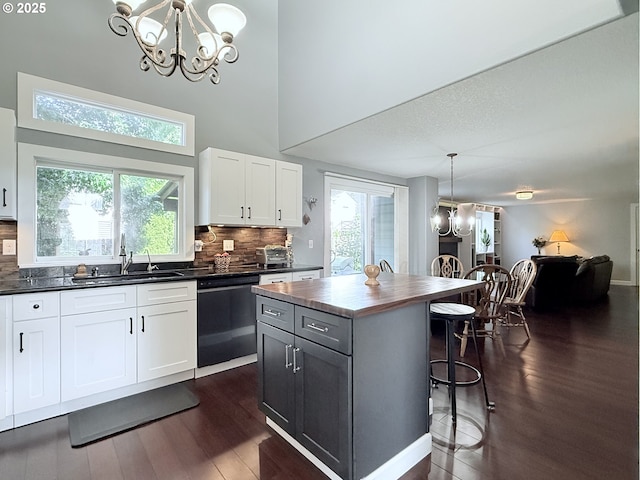 2942 NW Watkins Ct, Camas, WA 98607 - kitchen with dishwasher, a chandelier, a kitchen bar, dark wood finished floors, and backsplash