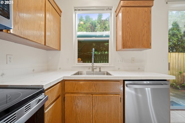 kitchen featuring tile countertops, appliances with stainless steel finishes, and a sink