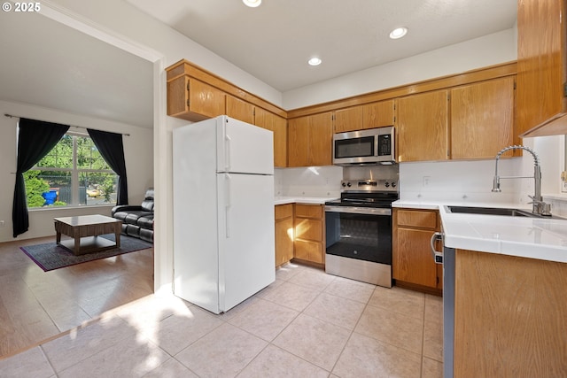 kitchen with a sink, light tile patterned floors, brown cabinetry, and stainless steel appliances