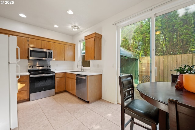 kitchen with light tile patterned flooring, a sink, light countertops, stainless steel appliances, and recessed lighting