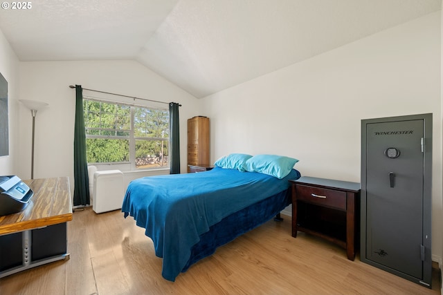 bedroom with light wood-type flooring and vaulted ceiling
